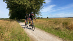 Impressie van de Roodtoer met twee snelle fietsers in sportieve kleding op een landweg 